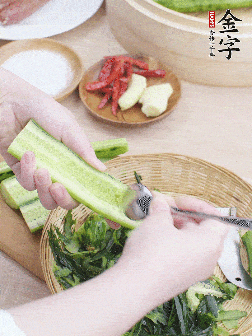 黃瓜削皮，對半切開，勺子挖去內(nèi)瓤，斜刀切片。青蒜斜刀切段。