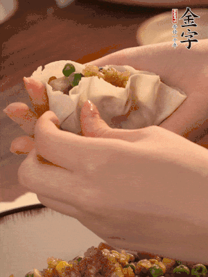 取一大勺餡料放進(jìn)餃子皮里，用大拇指按住頂部餡料，再用虎口掐出形狀。